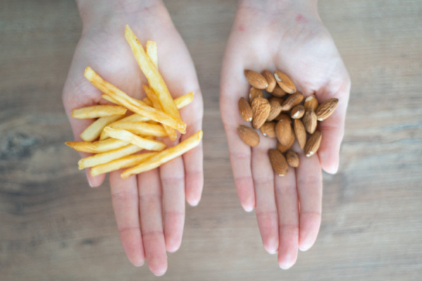 Two outstretched hands with french fries in one and almonds in the other